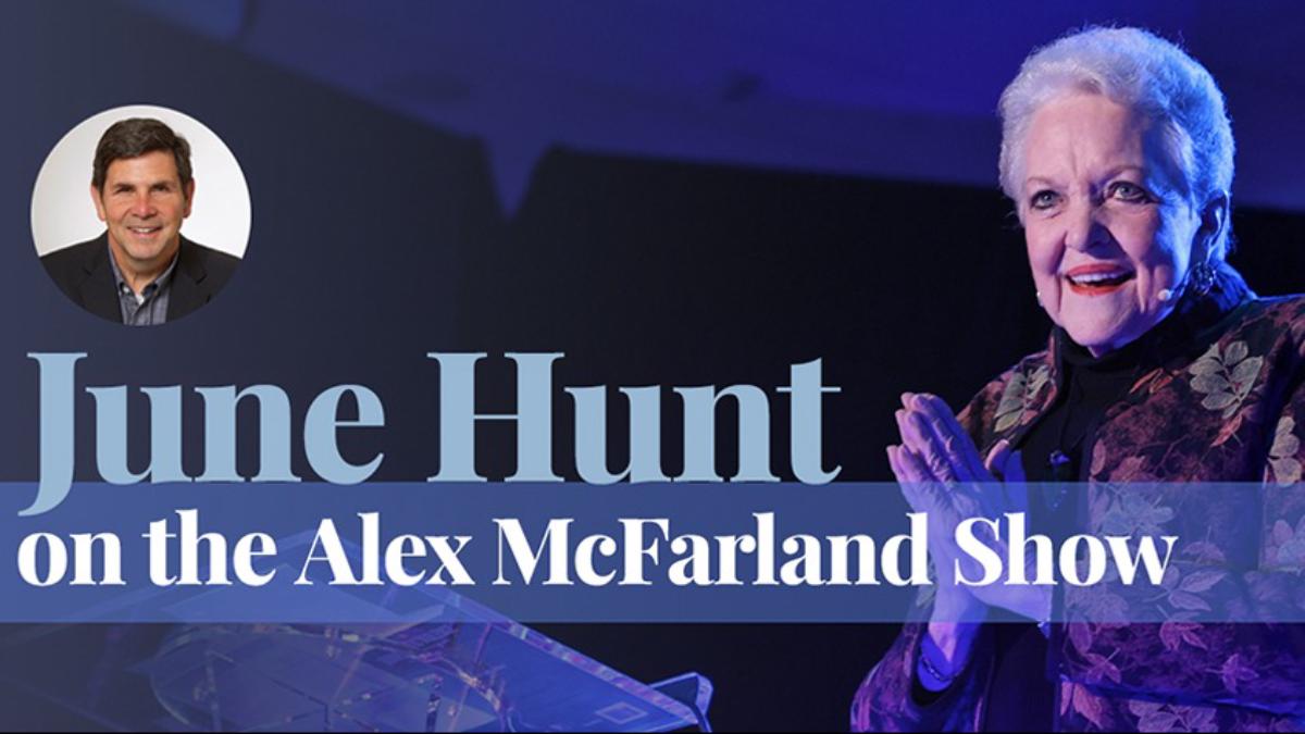 An woman stands on a stage with dramatic blue lighting, smiling and clasping her hands as she speaks at a podium. In the corner, a small circular inset shows a man’s portrait. Text on the image reads: ‘June Hunt on the Alex McFarland Show.’