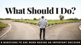 A person stands at a fork in the road, looking at two different paths stretching into the distance. Text on the image reads: ‘What Should I Do?’ and a subtitle says: ‘8 Questions to Ask When Making an Important Decision.’